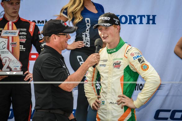 Rasmus Lindh från Kullavik intervjuas på podiet efter sin seger på Laguna Seca i Kalifornien. Kommande helg byter han sin Indy Pro 2000 formelbil mot en Porsche 911 GT3 Cup och startar i Carrera Cup-finalen på Mantorp Park.